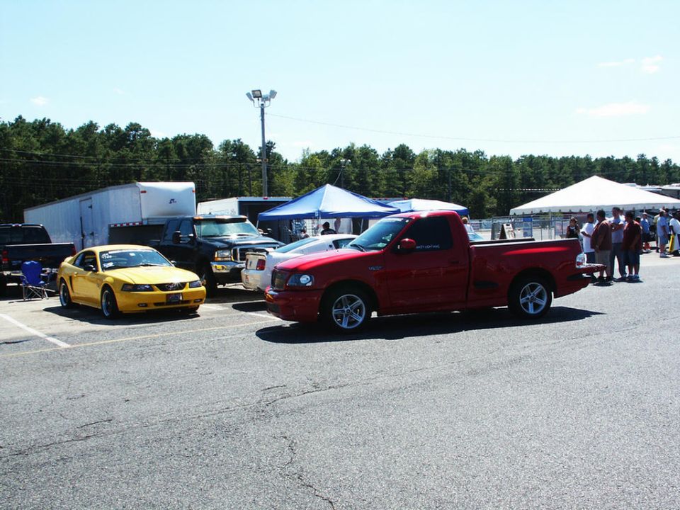 Red pickup truck and yellow coupe parked at a car show