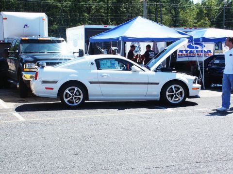 2001 Mercury Grand Marquis - White Ford Mustang with hood open at a car show, parked next to a black truck.