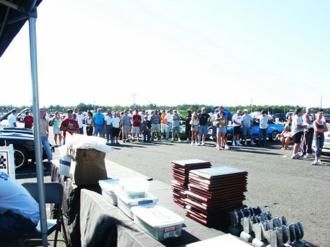 2001 Mercury Grand Marquis - An outdoor gathering of people and vehicles, possibly a car show, with awards displayed on tables.