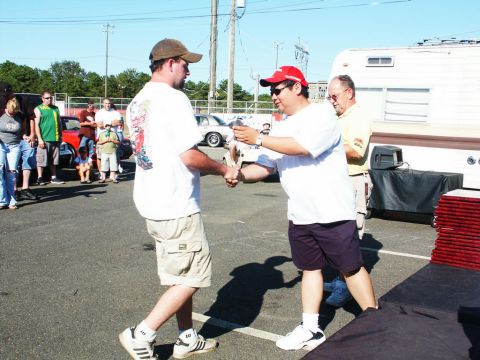 2001 Mercury Grand Marquis - Attendees gather at an outdoor event, with vehicles visible in the background and a trophy being presented.