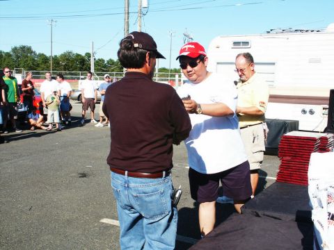 2001 Mercury Grand Marquis - Attendees mingle at a car show event, with vehicles and trailers visible in the background under a clear sky.