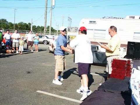 2001 Mercury Grand Marquis - An outdoor event with people and vehicles, possibly a car show, with two men exchanging a handshake.