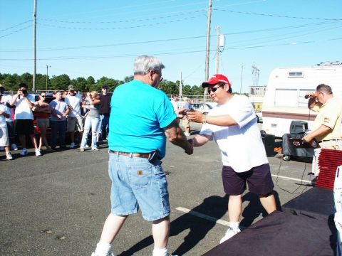 2001 Mercury Grand Marquis - Attendees mingle at an outdoor car show event, with a trailer and several vehicles in the background.
