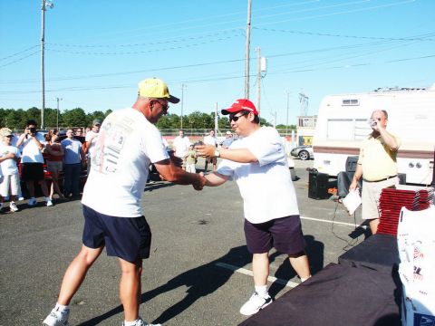 2001 Mercury Grand Marquis - Two men shake hands at an outdoor event, possibly a car show, with spectators and a trailer in the background.