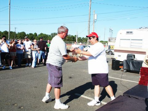 2001 Mercury Grand Marquis - An award or trophy is exchanged between two men at an outdoor gathering.