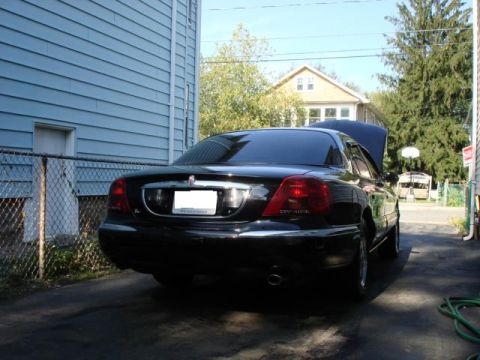 1997 Ford Crown Victoria - Rear view of a black sedan with the hood open, parked in a driveway.