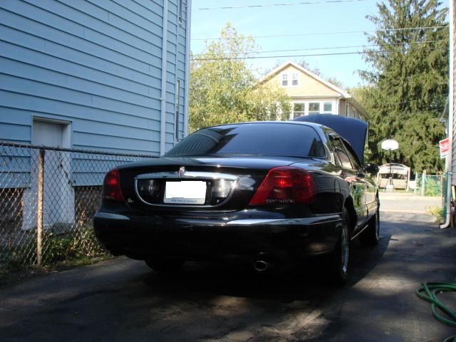 Black sedan rear view, hood open. Continental badging visible