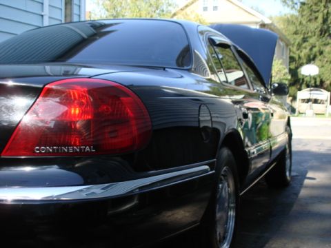 1997 Ford Crown Victoria - A black Lincoln Continental is parked in a driveway with its hood open, showing the engine bay.
