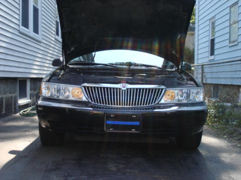 1997 Ford Crown Victoria - Front view of a black sedan with its hood open, revealing the engine bay. The vehicle features a prominent chrome grille and clear headligh…