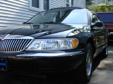 1997 Ford Crown Victoria - Front view of a black Lincoln Continental parked outside a house.