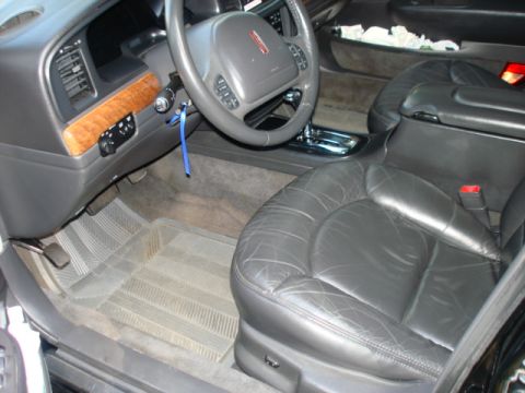 1997 Ford Crown Victoria - The interior of a Lincoln Town Car features leather seats and wood trim accents on the dashboard.