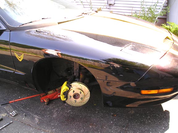 1994 Pontiac Trans Am front fender and hood, jack under car, front wheel removed showing upgraded brake caliper and rotor
