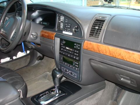 1997 Ford Crown Victoria - The interior of a Lincoln Town Car features wood grain trim, a digital climate control system, and a leather-wrapped steering wheel.