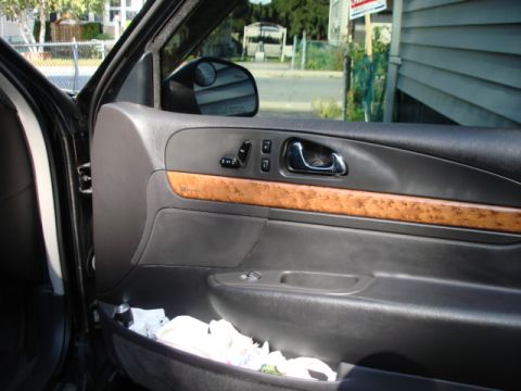 1997 Ford Crown Victoria - Interior view of a car door panel with wood trim and various controls.
