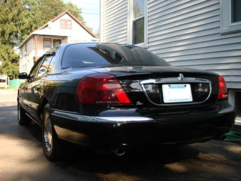 1997 Ford Crown Victoria - Rear view of a black Lincoln Continental parked in a driveway next to a house.