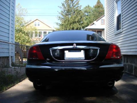 1997 Ford Crown Victoria - The rear of a black Lincoln Continental sedan is visible in a driveway.
