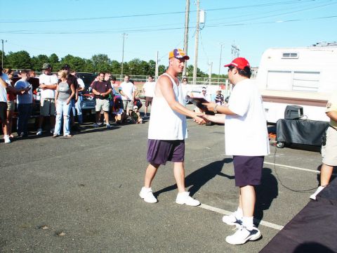 2001 Mercury Grand Marquis - Two men shake hands during an award presentation at an outdoor event, with vehicles and a trailer in the background.