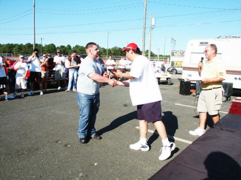 2001 Mercury Grand Marquis - People gather at a car show event, with awards being presented and a trailer visible in the background.
