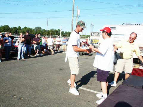 2001 Mercury Grand Marquis - Attendees gather at an outdoor car show, with vehicles visible in the background and a presentation taking place.