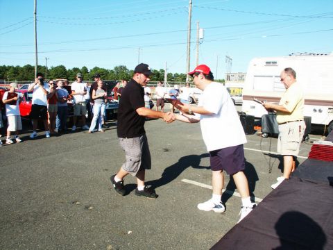 2001 Mercury Grand Marquis - Two men shake hands during an outdoor event, possibly a car show, with spectators watching.