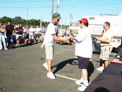 2001 Mercury Grand Marquis - Attendees receive awards at a car show event, with a trailer and crowd visible in the background.