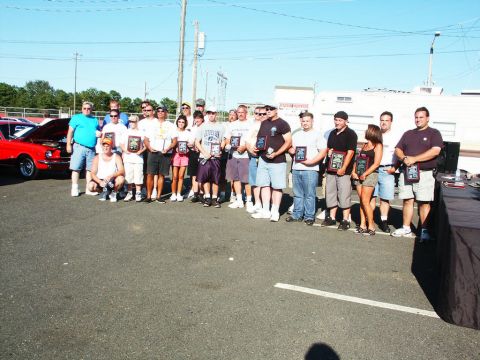 2001 Mercury Grand Marquis - A group of people are posing for a photo with awards, with a red car visible in the background.