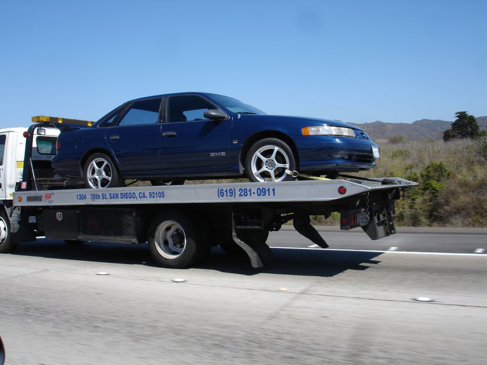 Blue 1992 Ford Taurus on a tow truck, side view