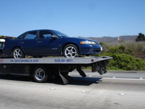 1992 Ford Taurus - Blue sedan being towed on a flatbed truck on a sunny day.