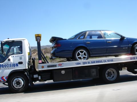 1992 Ford Taurus - A blue sedan is loaded onto a tow truck, likely being transported to or from San Diego.