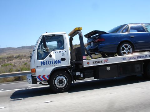 1992 Ford Taurus - A blue sedan is transported on a tow truck on a sunny day.