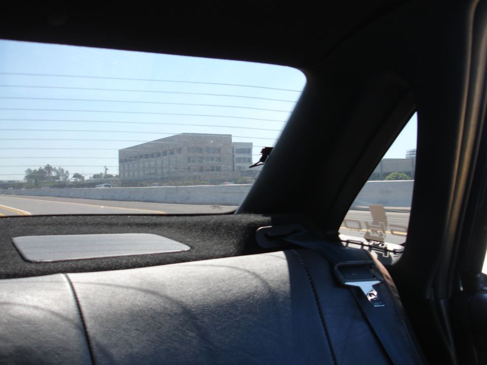 View from back seat of car looking out rear window at highway and building