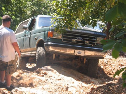1990 Ford Bronco - This Ford Bronco is navigating a rocky off-road course with a person observing the action.