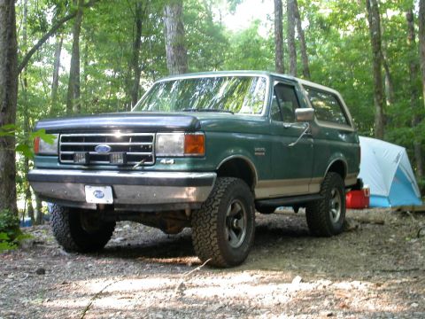 1990 Ford Bronco - Green 1990 Ford Bronco parked in a campsite with a tent set up.