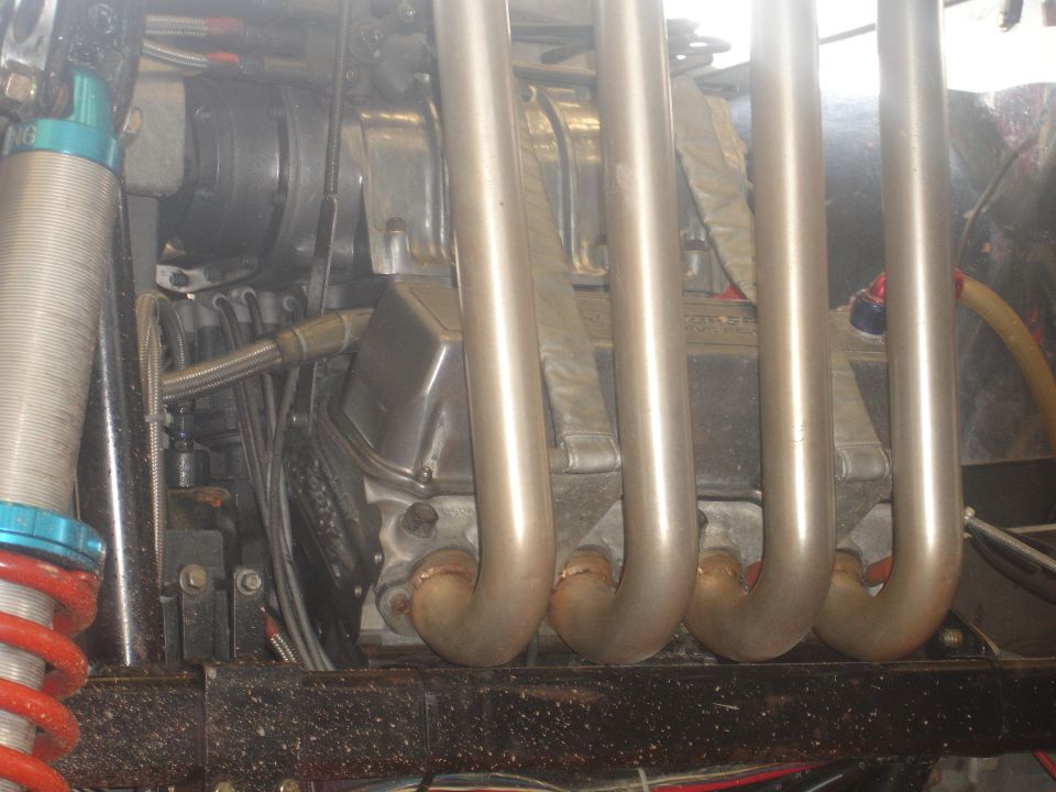 Engine block with chrome exhaust headers and suspension components visible