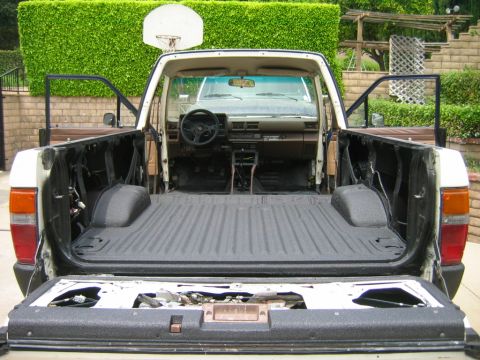 1985 Toyota 4Runner - The interior and bed of a pickup truck are visible with the tailgate down and doors open.
