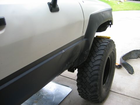 1985 Toyota 4Runner - Side view of a white SUV, possibly a Toyota 4Runner, with modifications to the fender and large tires.