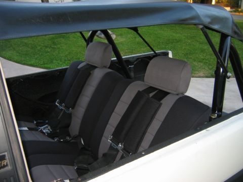 1985 Toyota 4Runner - The interior of a vehicle displays two rows of seats equipped with racing seatbelts and a roll cage.