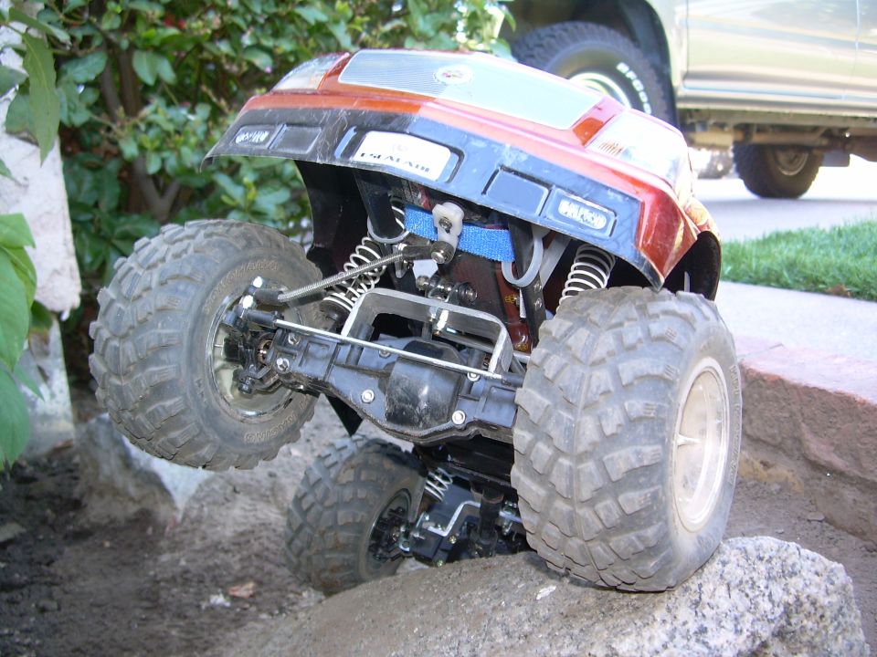 Rear underside of Escalade RC crawler showing rear axle, links and blue battery strap on dirt