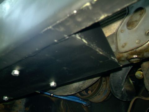 1989 Ford Bronco - Underside view of a vehicle, focusing on a bolted panel and mechanical components.