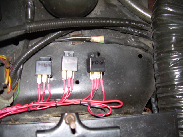 Three relays labeled HIGH, LOW and FOG mounted on a firewall with red wiring