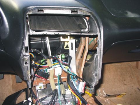 1993 Ford Probe - The interior of a 1993 Ford Probe reveals a complex and disorganized wiring harness behind the dashboard panel.