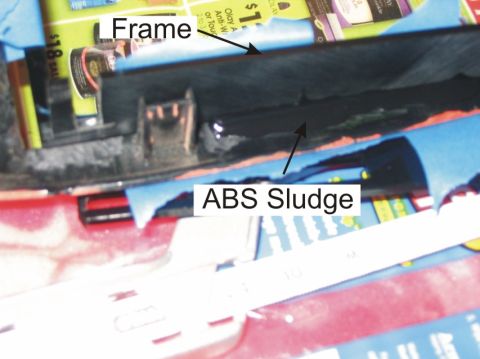 1993 Ford Probe - Close-up of a black plastic automotive component, likely a trim panel or frame piece, showing dark 'ABS sludge' residue along its surface,…