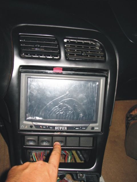 1993 Ford Probe - Interior center console/dash of a car showing a flip-out 'SUPER' LCD screen mounted in the double-DIN opening, with dual center air vents a…