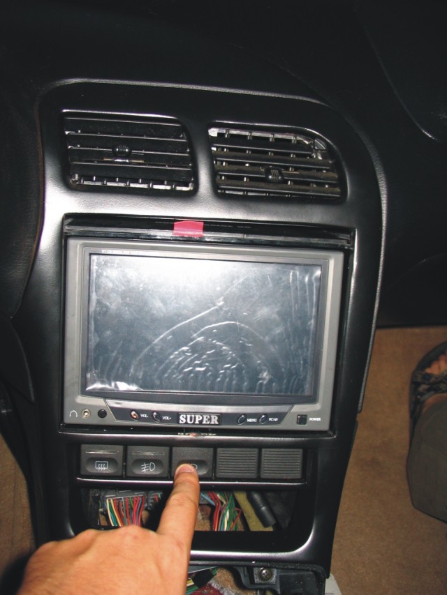 Car dash with 'SUPER' LCD screen, center vents, switches, and exposed wiring being worked on