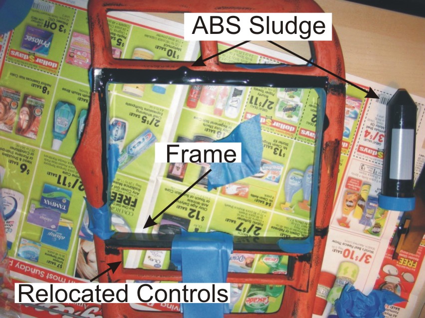 Red plastic frame with black ABS sludge sealant and blue tape on newspaper, labeled parts