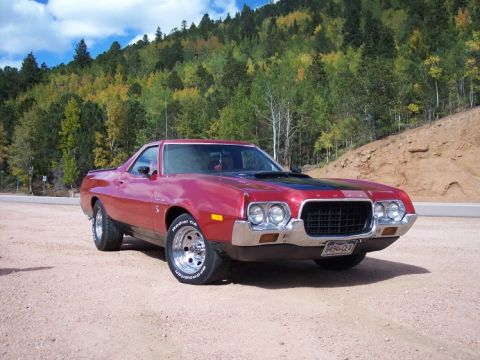 1972 Ford Ranchero - A red 1972 Ford Ranchero is parked on a dirt road with a wooded hillside in the background.
