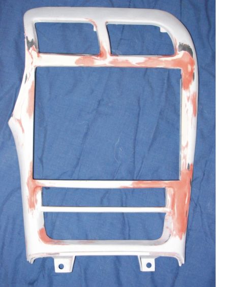 1993 Ford Probe - A plastic center dash/radio bezel trim panel laid on a blue cloth, showing multiple cutouts and being partially sanded with primer/filler i…