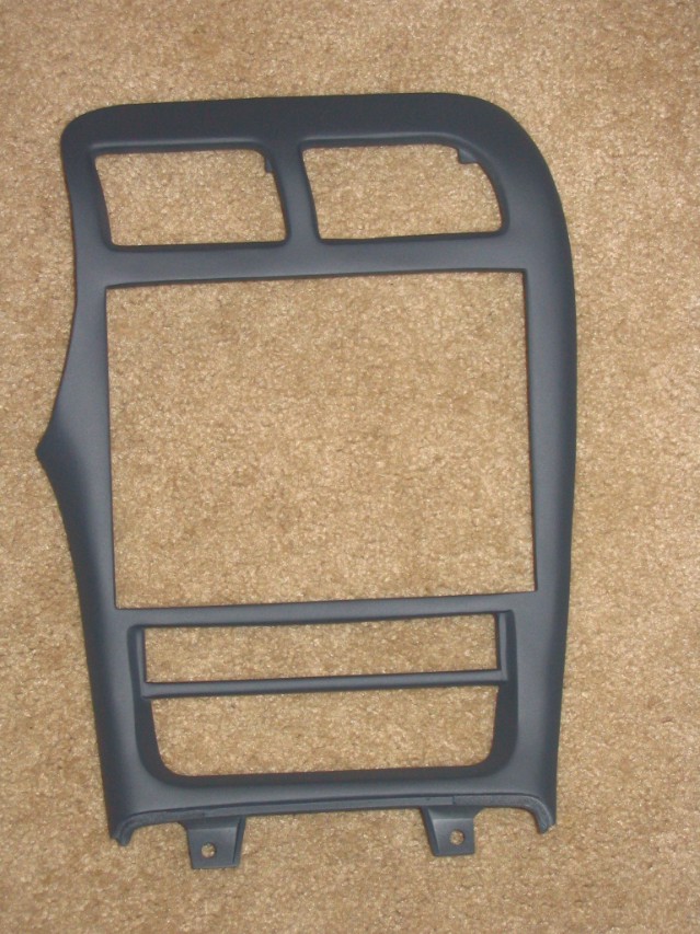 Gray dashboard center trim bezel with vent and radio cutouts on carpet