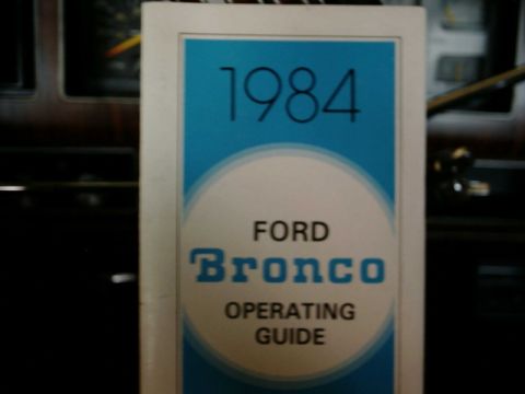 1984 Ford Bronco - A close-up view of a 1984 Ford Bronco operating guide resting on the vehicle's dashboard.