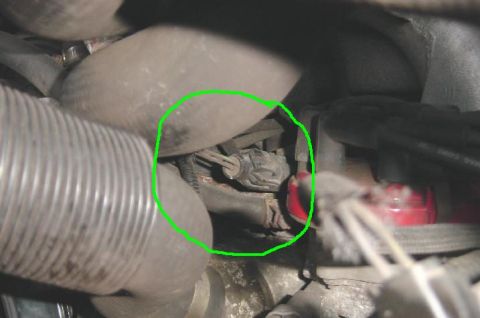 1991 Ford Bronco - A green circle highlights a wiring harness connector within the engine bay, surrounded by hoses and cables.